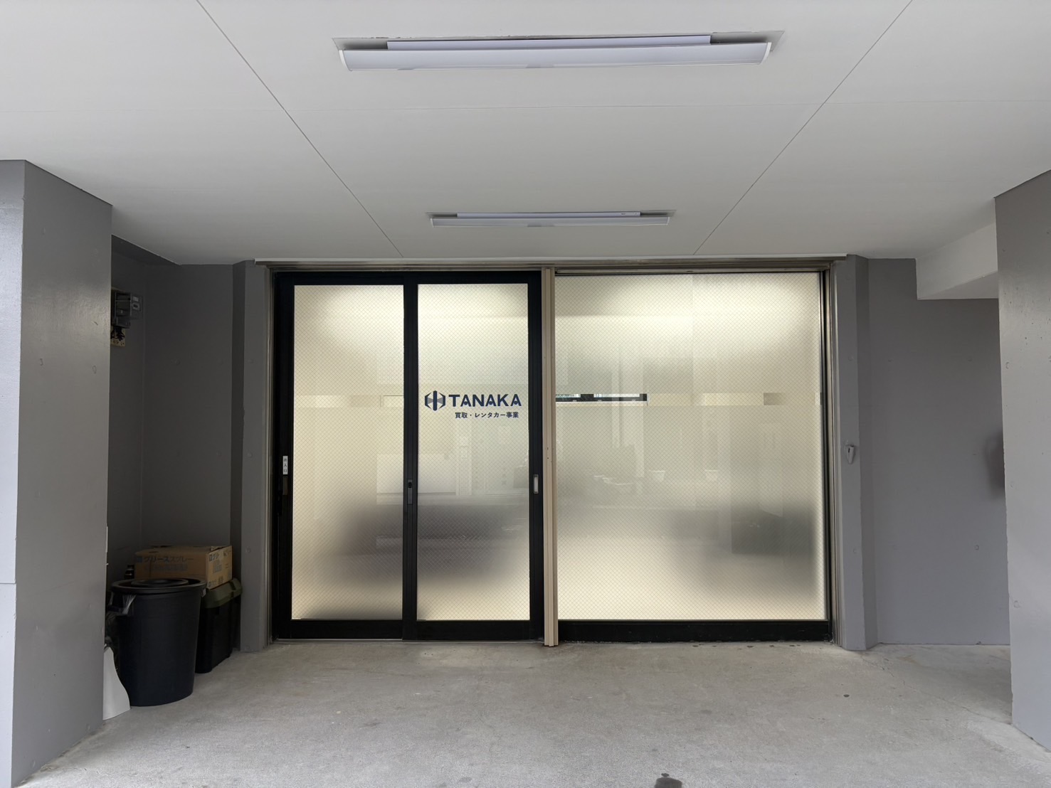 TANAKAのロゴと買取・レンタカー事業の表記がある店舗入口
